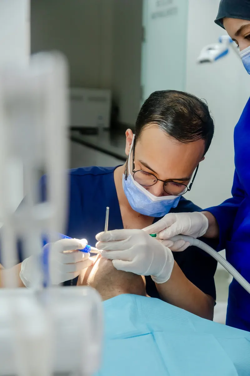 Dentist in blue scrubs treating a patient in the clinic - Dragonzay Photography