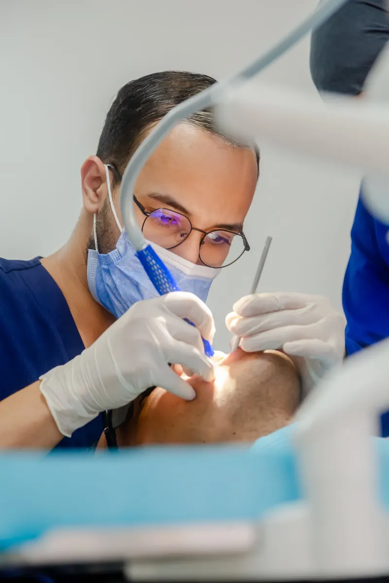 Dentist in blue scrubs treating a patient in the clinic - Dragonzay Photography