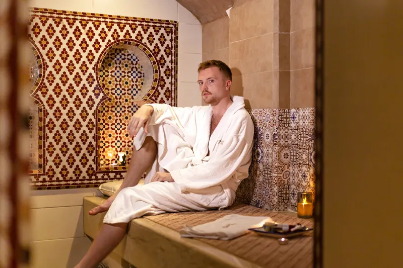 Client in a bathrobe sitting in a zellige hammam - Dragonzay Photography