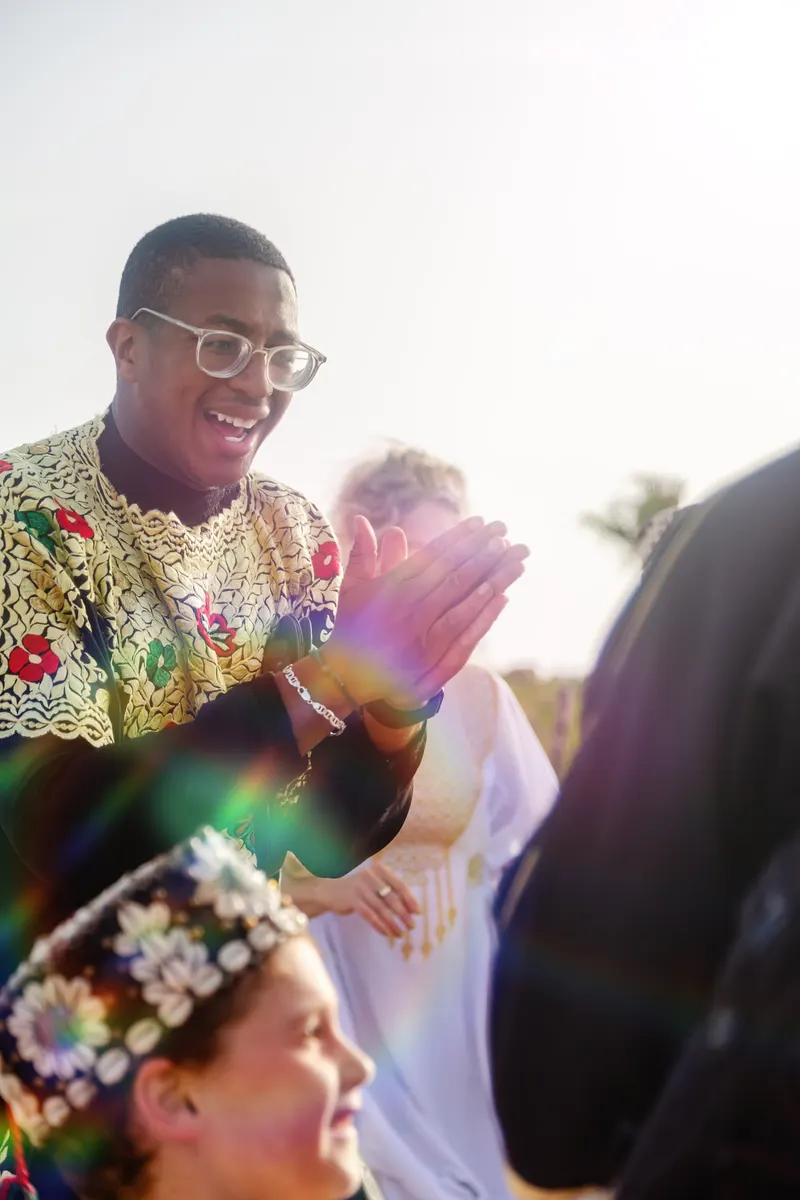 Guest in an embroidered kaftan applauding at a Moroccan wedding - Dragonzay Photography