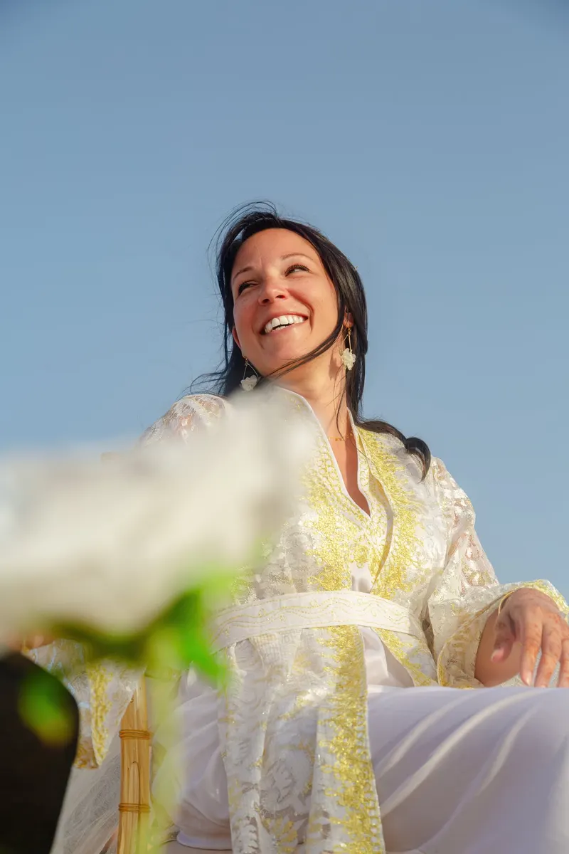 Smiling bride in an embroidered dress against a blue sky - Dragonzay Photography