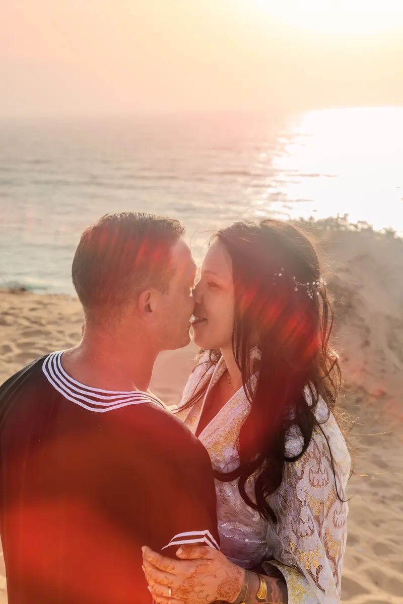 Newlyweds forehead to forehead facing the ocean - Dragonzay Photography