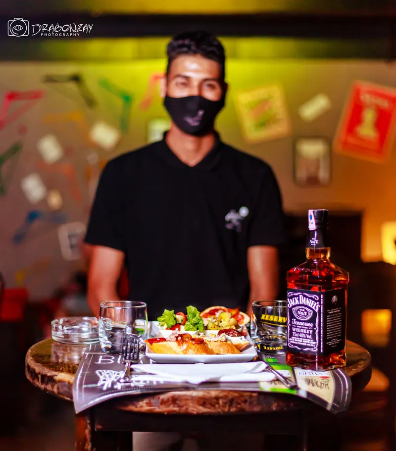 Masked waiter presenting a dish and a bottle at the bar - Dragonzay Photography