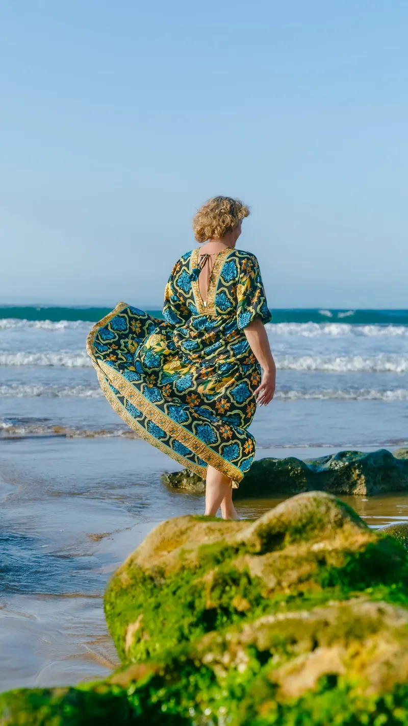 Photoshoot in a turquoise and gold printed dress facing the ocean - Dragonzay Photography