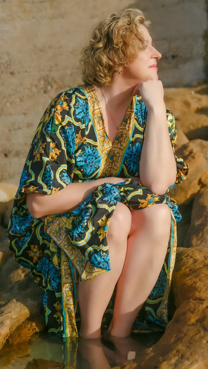 Photoshoot in a turquoise and gold printed dress facing the ocean - Dragonzay Photography