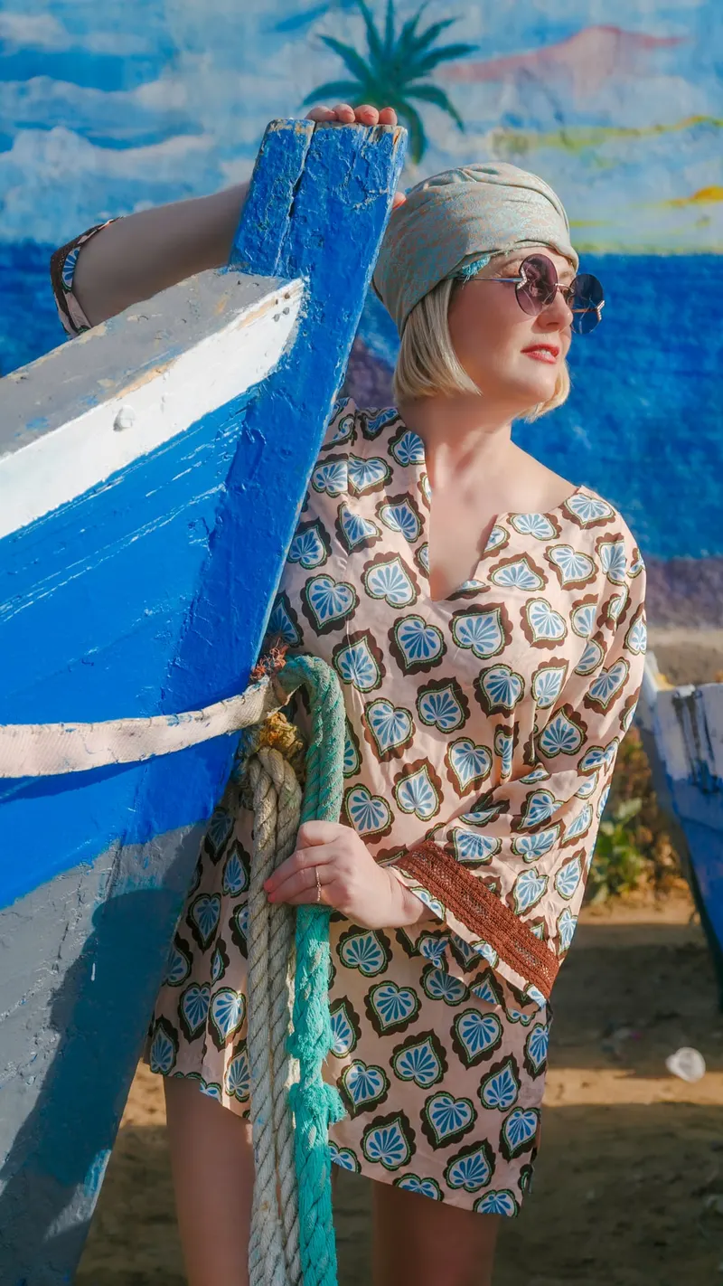 Portrait in an embroidered kaftan in front of a blue fishing boat - Dragonzay Photography