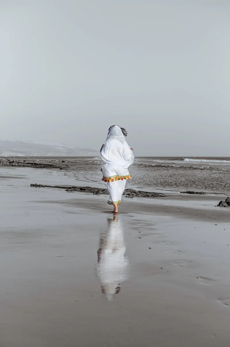Figure in white walking on the beach at low tide - Dragonzay Photography
