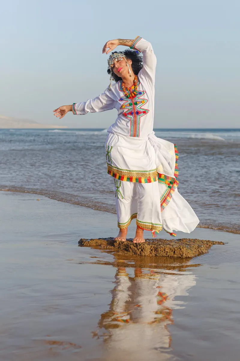 Dancing in a white dress on a rock facing the sea - Dragonzay Photography