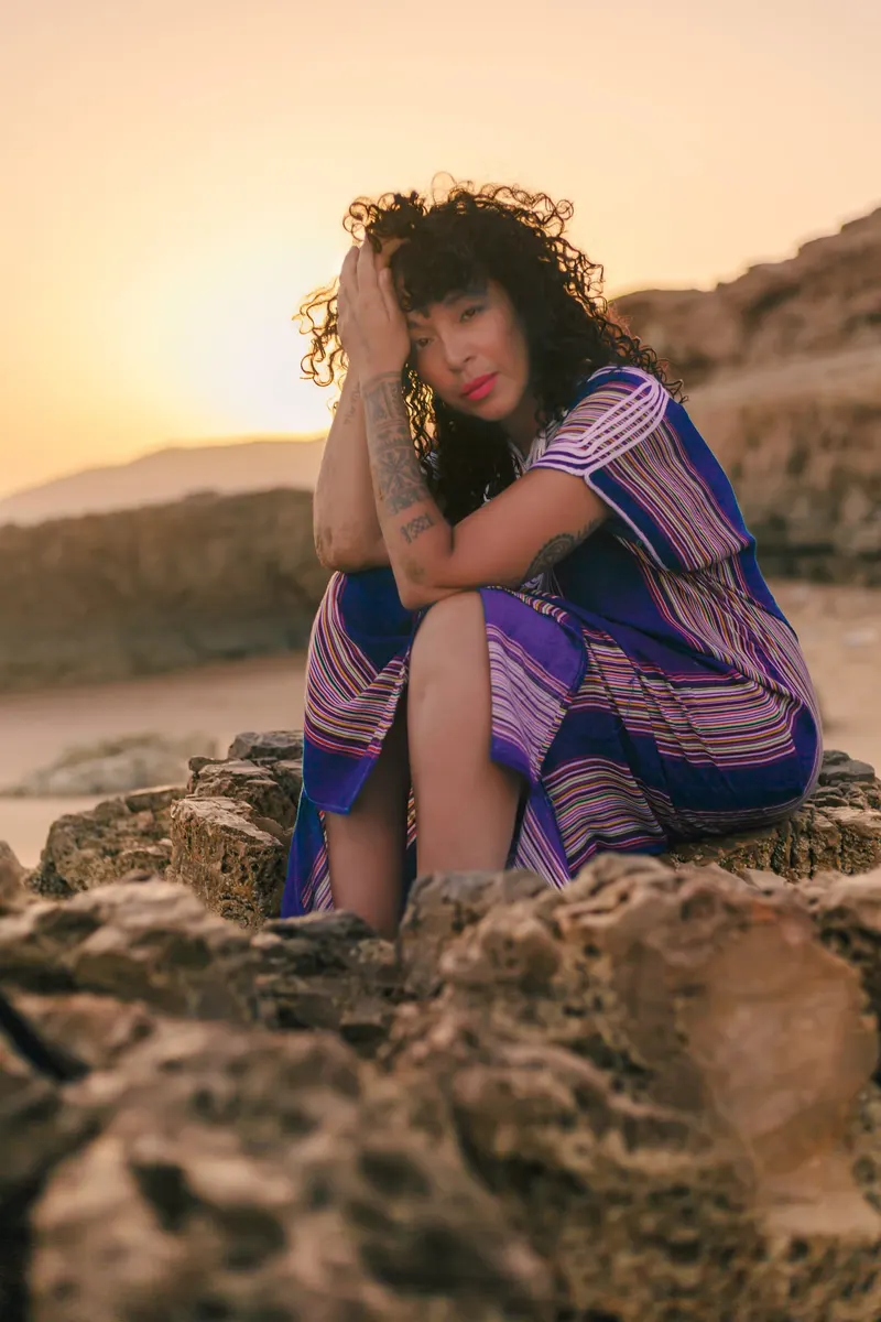 Woman sitting on the rocks at sunset - Dragonzay Photography