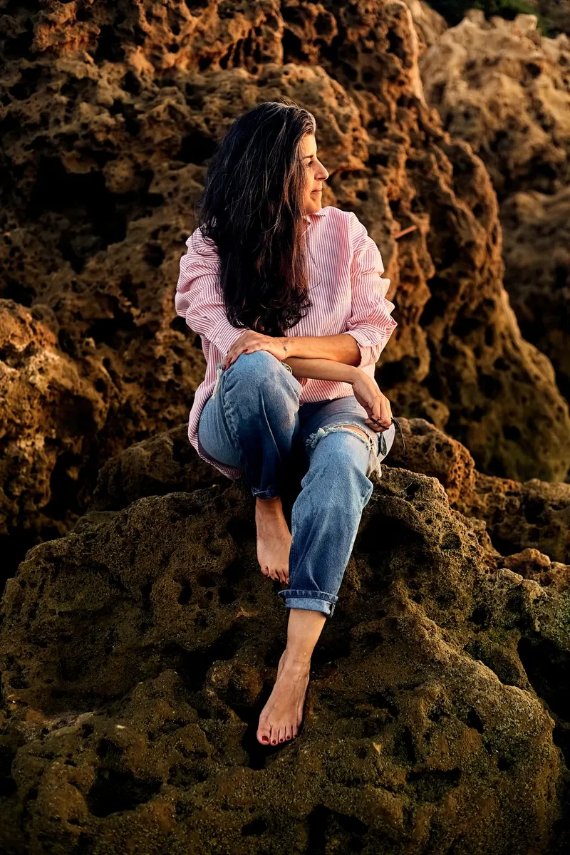 Young woman in jeans and a pink shirt on the rocky beach - Dragonzay Photography