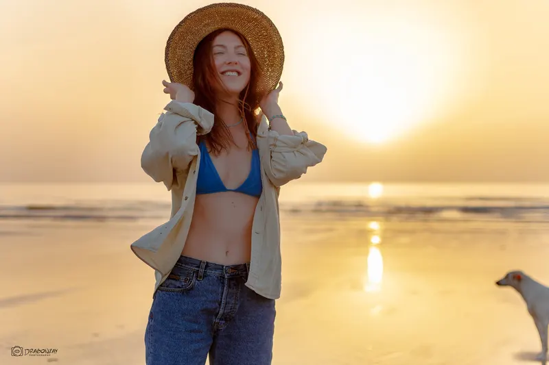 Woman in a straw hat and blue top facing the setting sun - Dragonzay Photography