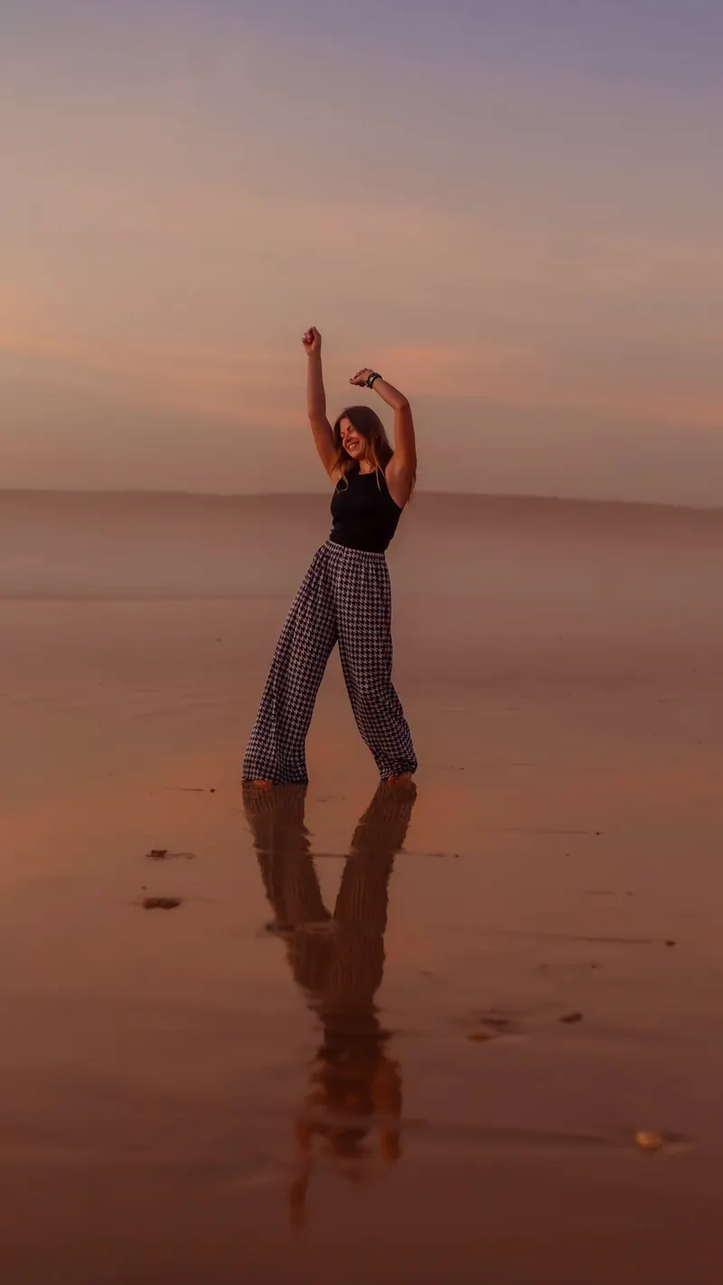 Woman in flowing trousers standing in the water on the beach - Dragonzay Photography