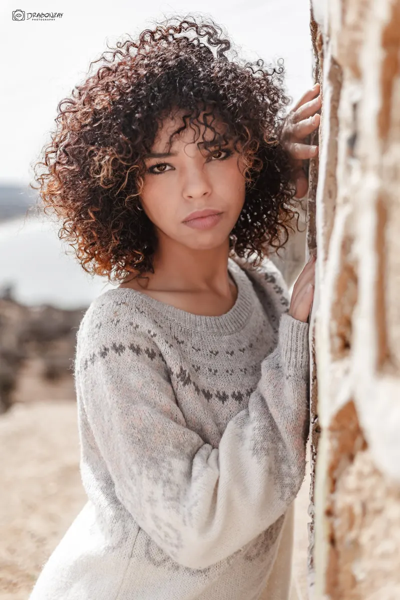 Portrait of a young curly-haired woman in a white sweater - Dragonzay Photography