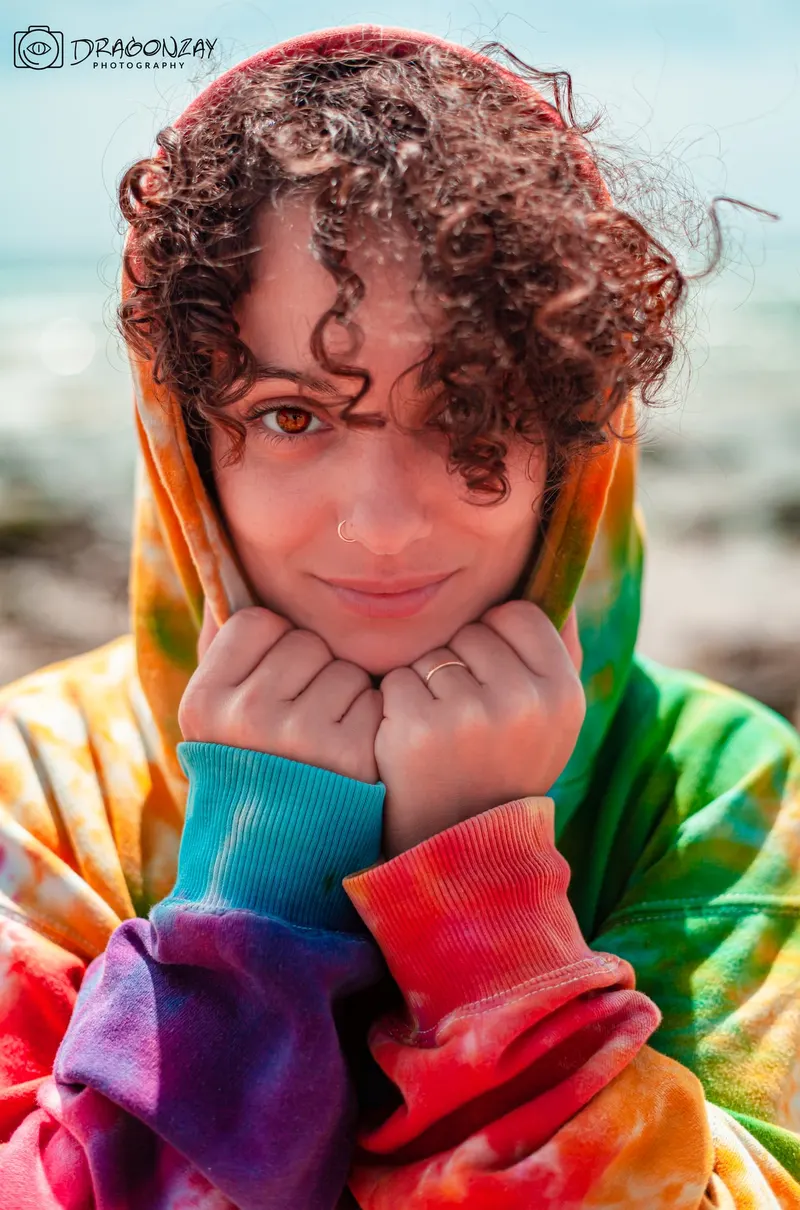 Joyful portrait in a multicoloured tie-dye hoodie on the beach - Dragonzay Photography