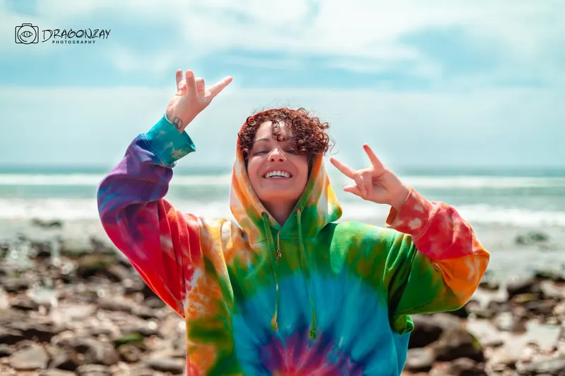 Joyful portrait in a multicoloured tie-dye hoodie on the beach - Dragonzay Photography