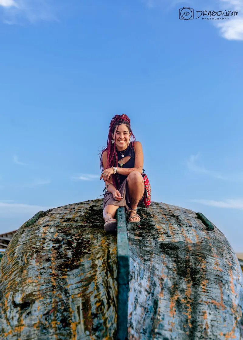 Woman sitting on a rock facing the ocean - Dragonzay Photography