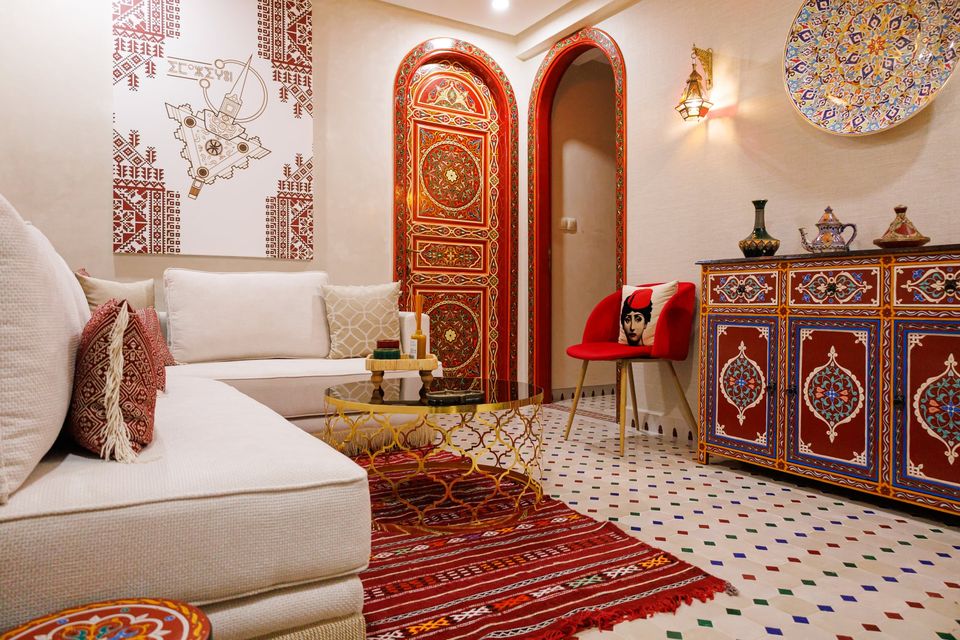 Salon marocain avec banquettes blanches, tapis rouge et portes peintes - Dragonzay Photography